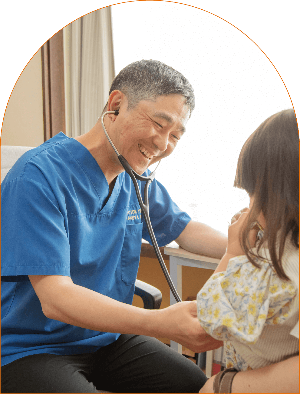 院長・田村先生が子どもに聴診器を当てながら、子どもの様子に微笑んでいます。